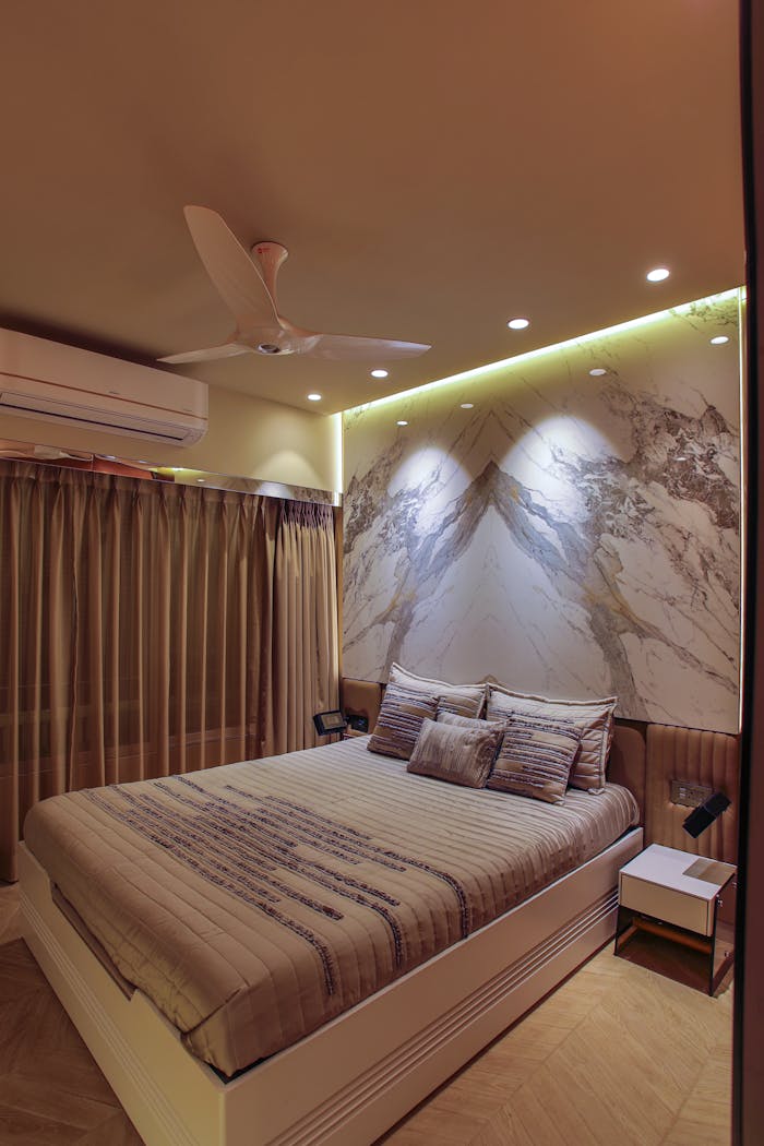 services-06 Stylish bedroom with ambient lighting and contemporary decor features a ceiling fan and artistic wall design.